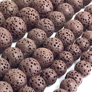 May include: A strand of brown lava rock beads. The beads are round and have a porous texture.