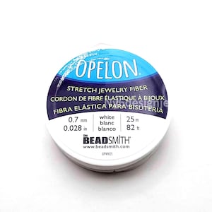 May include: A round spool of white Opelon stretch jewelry fiber by The Beadsmith. The label features blue and dark purple text, indicating a diameter of 0.7 mm or 0.028 inches and a total length of 25 meters or 82 feet. The model number is OPWH25.