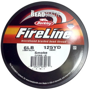 May include: A spool of black FireLine microfused braided bead thread fishing line. The spool is labeled with the brand name "Berkley FireLine", the line weight "6LB", the line diameter "0.006in avg.dia", the line length "125YD", and the product code "1392826". The spool also has a barcode and the text "Smoke FLFSH6-42".