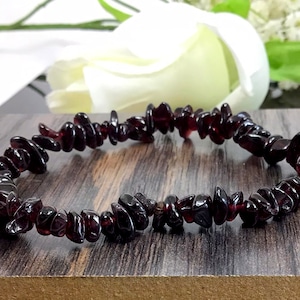 May include: A dark red gemstone chip bracelet made with small, irregular shaped chips. The bracelet is made with natural stones and is approximately 7 inches in length.