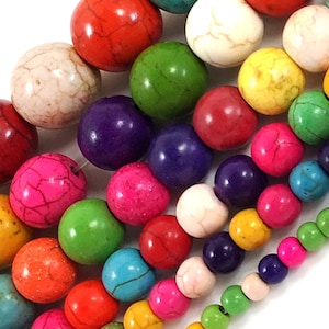 May include: A variety of colorful round beads made of natural stone. The beads are in shades of red, green, blue, purple, white, and yellow. The beads are all different sizes and have a natural, rough texture.