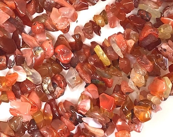 May include: A strand of carnelian chip beads in various shades of red, orange, and brown. The chips are irregular in shape and size, creating a natural and earthy look.