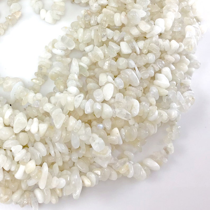 May include: A strand of white moonstone chip beads. The beads are irregular in shape and have a slightly iridescent sheen.