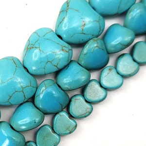 May include: A strand of turquoise heart-shaped beads. The beads are a light blue color with darker blue veins running through them.