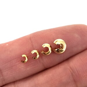 May include: Four gold-colored jump rings of different sizes. The rings are open and have a smooth, polished finish.