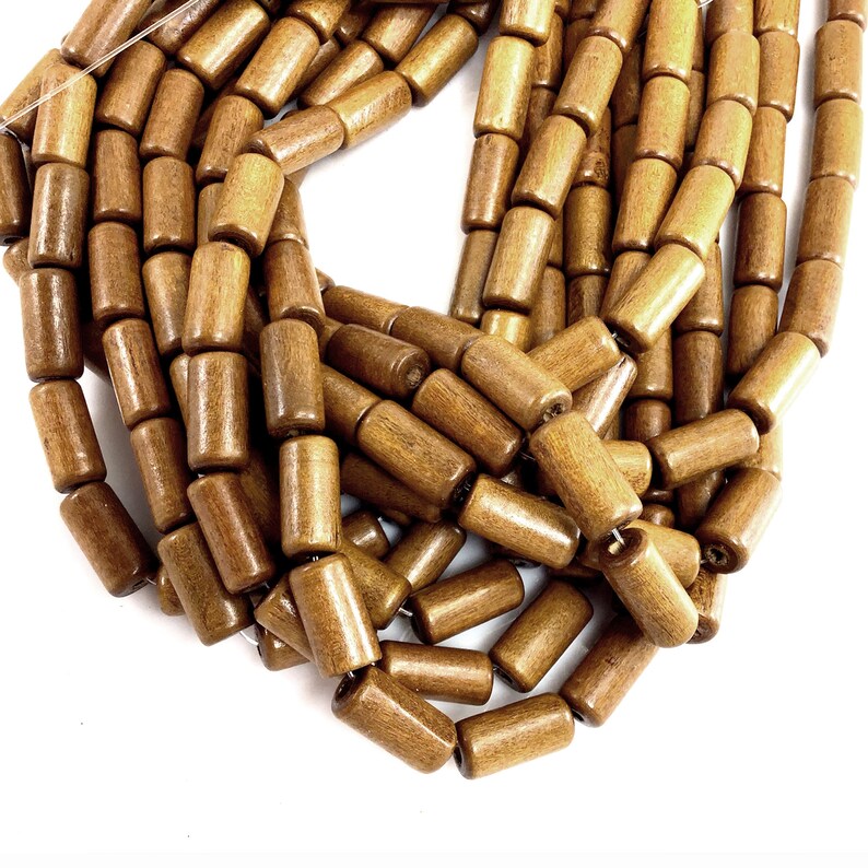 May include: Strands of brown wooden beads. The beads are cylindrical with rounded edges and a smooth, polished finish. The beads are strung together, creating a necklace or craft supply.