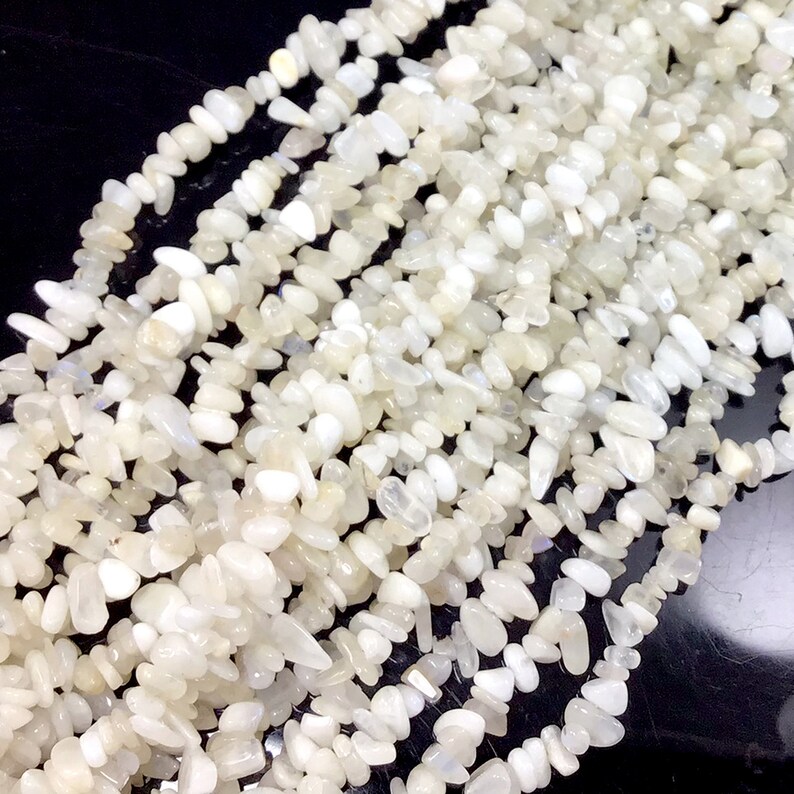 May include: A strand of white moonstone chip beads. The beads are irregular in shape and have a slightly iridescent sheen.
