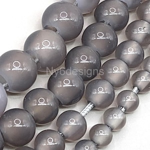 May include: A strand of gray gemstone beads. The beads are round and have a smooth, polished finish. The beads are strung on a silver cord.
