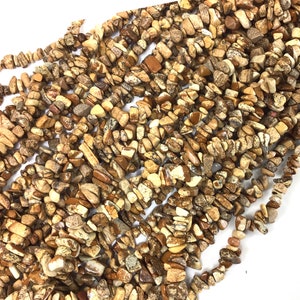 May include: A strand of brown and beige gemstone chips. The chips are irregular in shape and size, and have a mottled appearance.