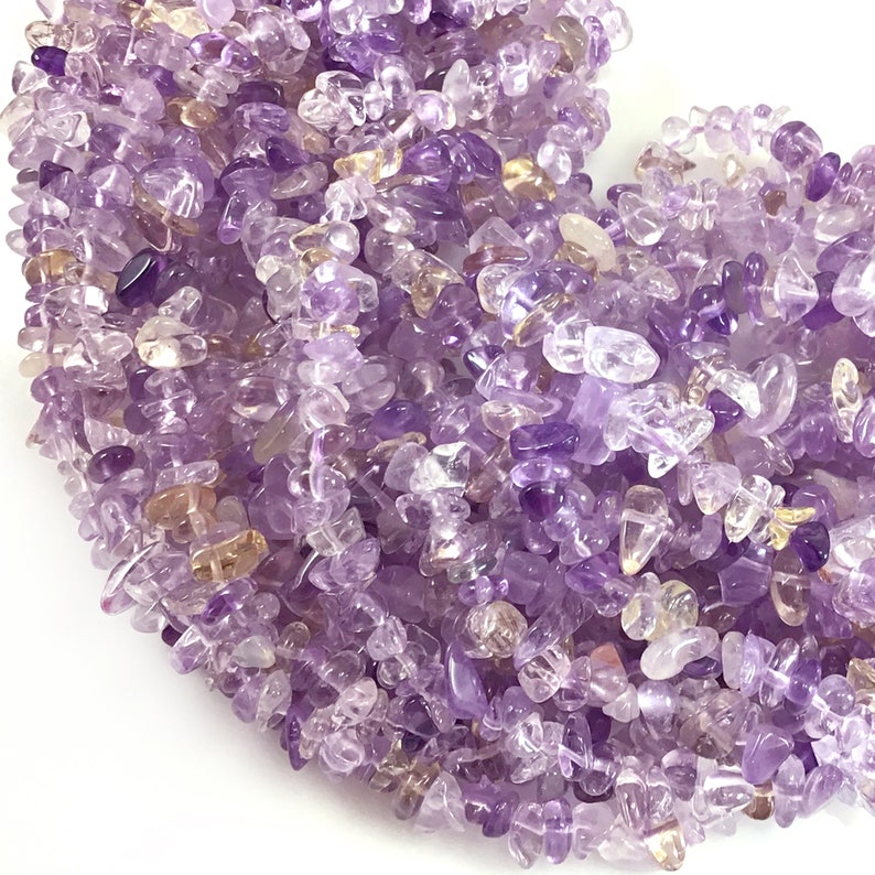 May include: A strand of amethyst chip beads, featuring a mix of light and dark purple hues. The chips are irregular in shape and size, creating a natural and organic look.