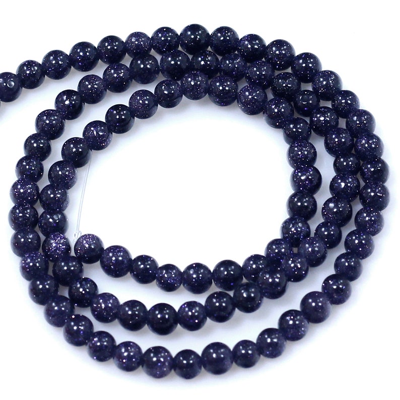 May include: A strand of dark blue gemstone beads with a speckled, starry appearance. The beads are round and smooth, and they are strung on a clear thread.