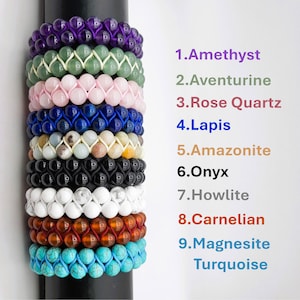 May include: A stack of 9 colorful gemstone bracelets, each with a different type of stone. The bracelets are arranged in order from top to bottom: Amethyst, Aventurine, Rose Quartz, Lapis Lazuli, Amazonite, Onyx, Howlite, Carnelian, and Magnesite Turquoise.