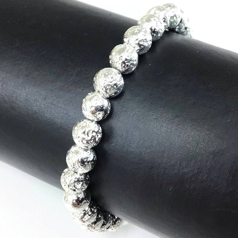 May include: Silver beaded bracelet with textured, spherical beads. The bracelet is displayed against a black background, showcasing the reflective quality of the beads. The beads are approximately 0.5 inches in diameter.