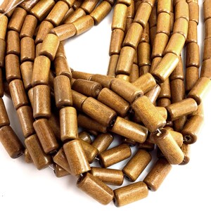 May include: Close-up of a collection of brown wooden beads. The beads are cylindrical with rounded edges and a smooth, polished finish. They are strung together, creating a textured and natural aesthetic. Ideal for jewelry making and craft projects.