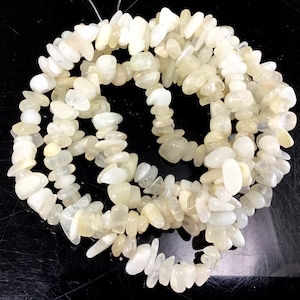 May include: A strand of white moonstone chip beads. The beads are irregular in shape and have a slightly translucent appearance.