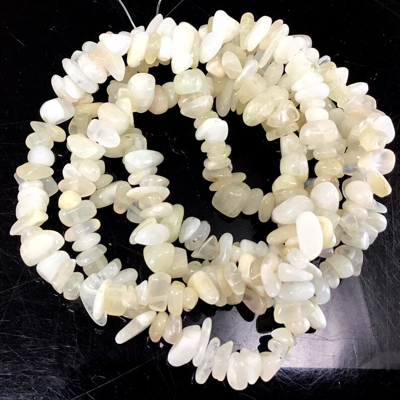 May include: A strand of white moonstone chip beads. The beads are irregular in shape and have a slightly translucent appearance.