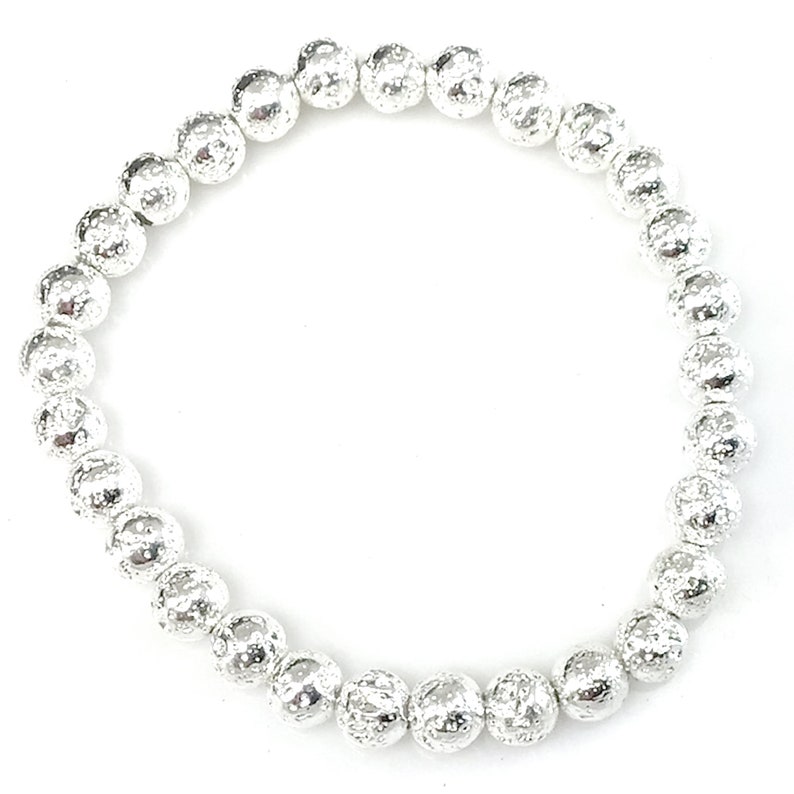 May include: A silver beaded bracelet with textured, spherical beads. The bracelet is made of small, round beads strung together, creating a flexible and stylish accessory. The beads have a hammered or textured appearance.