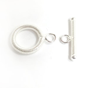May include: Silver tone toggle clasp with a spring ring. The clasp is made of metal and has a smooth finish.