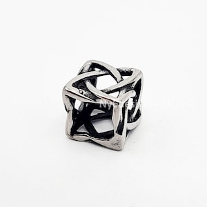 May include: A silver-colored, cube-shaped bead with an intricate, interwoven design. The bead has a Celtic knot pattern, with open spaces creating a geometric, three-dimensional effect. The bead is likely made of stainless steel or a similar metal.
