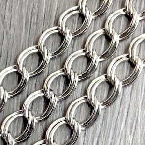 May include: Silver chain with a twisted oval link design. The chain is made of metal and has a shiny finish.