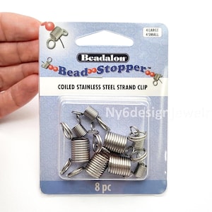May include: A package of Beadalon Bead Stopper coiled stainless steel strand clips. The package contains 8 pieces, with 4 large and 4 small clips. The package has a blue and white design with the brand name and product information.