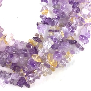 May include: A strand of chip amethyst and citrine gemstone beads. The beads are a mix of purple, yellow, and clear.