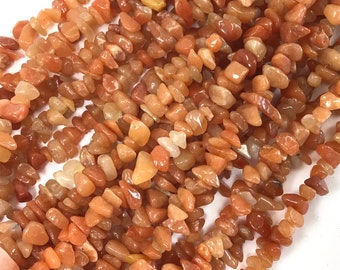 May include: A strand of orange and brown chip-shaped carnelian gemstone beads. The beads are irregular in shape and size, with a natural, polished finish.