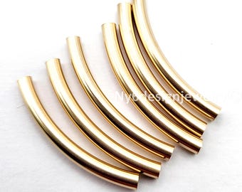 Op de afbeelding: Een verzameling goudkleurige, gebogen metalen buizen, waarschijnlijk voor het maken van sieraden, op een witte achtergrond. De buizen hebben een gladde, gepolijste afwerking die het licht reflecteert. Deze componenten kunnen worden gebruikt voor armbanden, kettingen of andere decoratieve items.