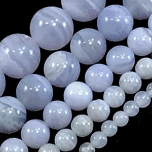 May include: A strand of blue agate beads in various sizes. The beads are round and have a smooth, polished finish. The beads are a light blue color with white streaks.
