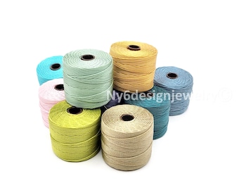 May include: A collection of colorful spools of waxed cord in various shades, including teal, pink, green, yellow, and blue. The spools are arranged in a cluster, showcasing the different colors and textures of the cord. Ideal for crafting and jewelry making.