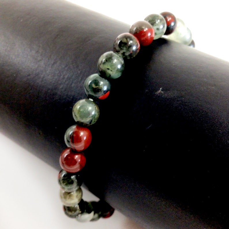 May include: A beaded bracelet with alternating green and red beads. The green beads have a speckled pattern and the red beads are a solid color.