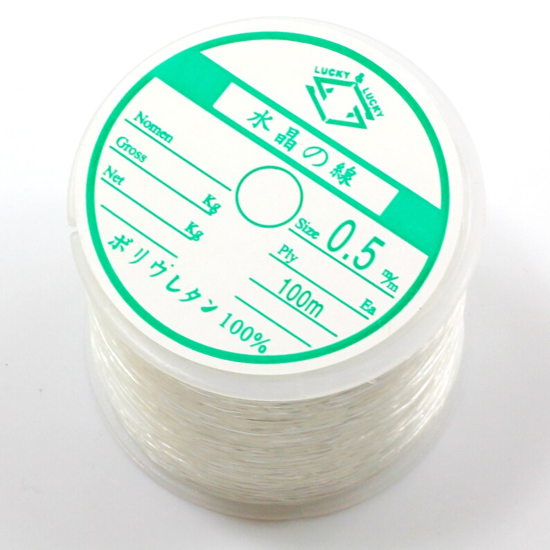 May include: A spool of white elastic cord labeled "Lucky Lucky" with the text "Water Crystal Line" in Japanese. The spool is labeled with the size "0.5 mm", "100m", and "Polyurethane 100%".
