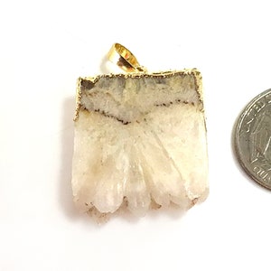 May include: A white agate pendant with a gold-plated edge. The pendant is shaped like a rectangle with a jagged edge. The pendant is about the size of a US quarter.