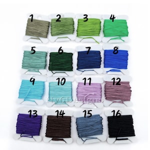 May include: A set of 16 spools of waxed cord in various colors, including green, blue, purple, brown, and gray. Each spool is labeled with a number from 1 to 16.