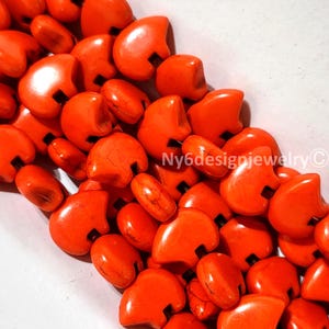 May include: A collection of bright orange, heart-shaped beads with a smooth, polished finish and visible natural veining. The beads are strung together in a dense cluster. The text Ny6designjewelry is printed in white on the right side.