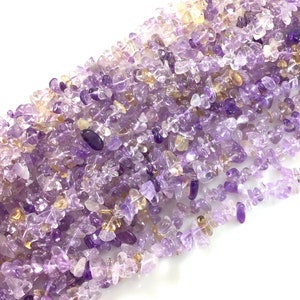 May include: A strand of chip amethyst and citrine gemstone beads. The beads are a mix of light purple and yellow, and are all irregular in shape.