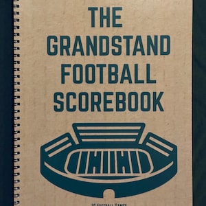 May include: A spiral-bound notebook with a kraft paper cover. The cover features the text "THE GRANDSTAND FOOTBALL SCOREBOOK" in teal, along with a teal stadium graphic. The text "30 FOOTBALL GAMES" is at the bottom.
