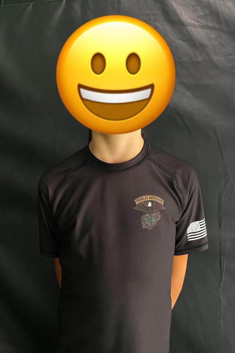 May include: A dark gray short-sleeved shirt with the text "FIDELIS DEFENSE" above an eagle and globe design. The shirt has a small American flag on the sleeve.