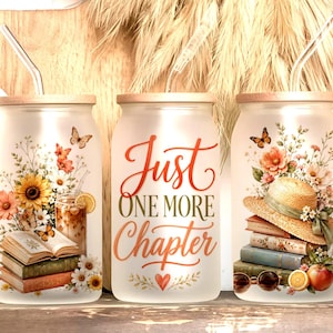 Puede incluir: Tres vasos de vidrio esmerilado con tapas de madera y pajitas de vidrio. Cada vaso presenta diseños florales, mariposas y el texto "Just One More Chapter". Un vaso tiene una pila de libros, un girasol y un vaso de té helado.
