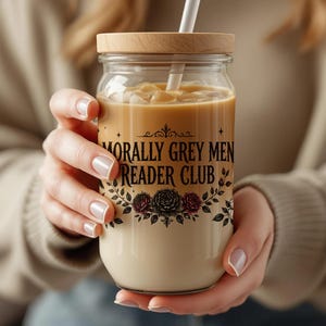 Glass jar with "Morally Grey Men Reader Club" text holding a creamy beverage with straw.