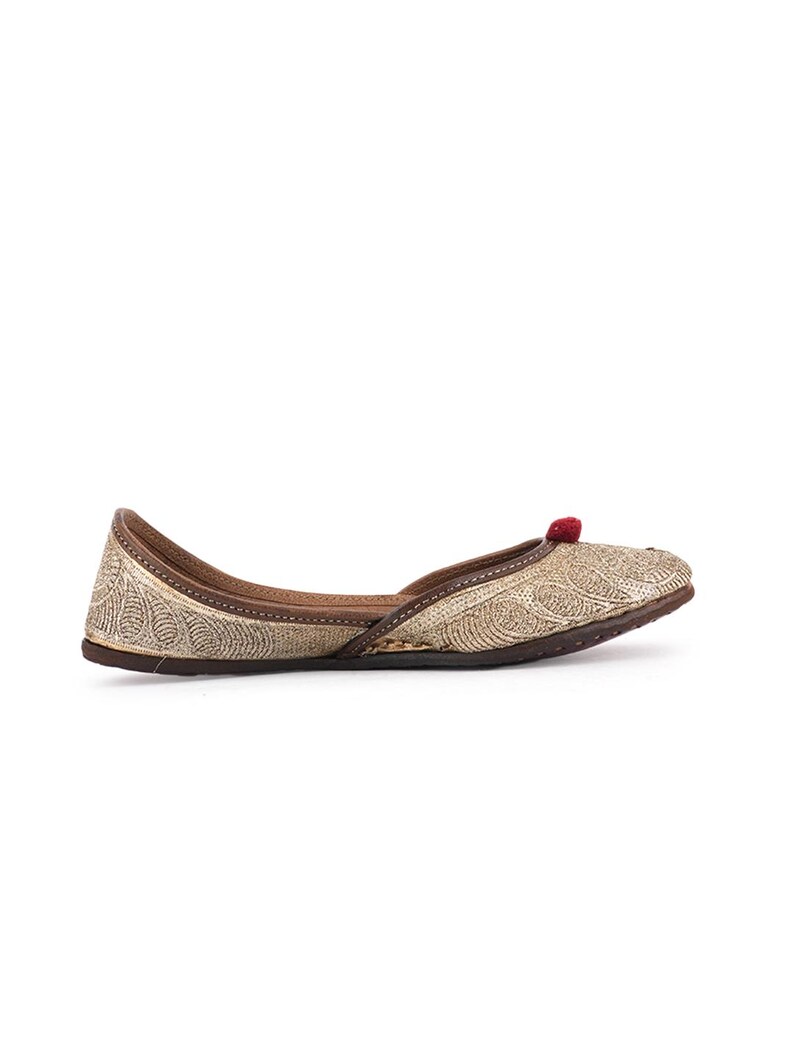 Pode incluir: Sapato raso dourado com bordados intrincados e um pequeno detalhe de pompom vermelho. O sapato tem sola e acabamento marrom. Este cal&ccedil;ado elegante foi projetado para conforto e estilo. Ideal para ocasi&otilde;es especiais ou uso di&aacute;rio.