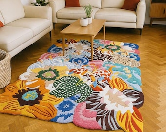 May include: A colorful floral rug with a variety of shapes and colors, including yellow, orange, blue, pink, and green. The rug is placed on a hardwood floor in a living room setting, with a cream-colored sofa and wooden coffee table.