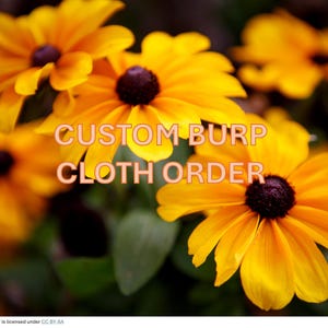May include: Close-up of vibrant yellow flowers with dark brown centers and green leaves. The text "CUSTOM BURP CLOTH ORDER" is overlaid on the image. The flowers are in focus, creating a bright and cheerful image.