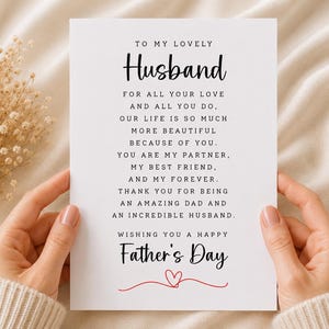 以下が含まれることがあります： 黒い文字で「TO MY LOVELY Husband FOR ALL YOUR LOVE AND ALL YOU DO. OUR LIFE IS SO MUCH MORE BEAUTIFUL BECAUSE OF YOU. YOU ARE MY PARTNER, MY BEST FRIEND, AND MY FOREVER. THANK YOU FOR BEING AN AMAZING DAD AND AN INCREDIBLE HUSBAND. WISHING YOU A HAPPY Father's Day」と印刷された白い長方形のグリーティングカード。テキストの下には小さな赤いハートのグラフィックがあります。
