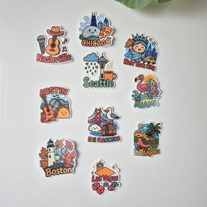 Set di 10 adesivi con cartoni animati di città degli Stati Uniti - Divertenti adesivi in vinile opaco per laptop e bottiglie / Souvenir di viaggio iconici: New York, Las Vegas, Los Angeles, Seattle, Austin