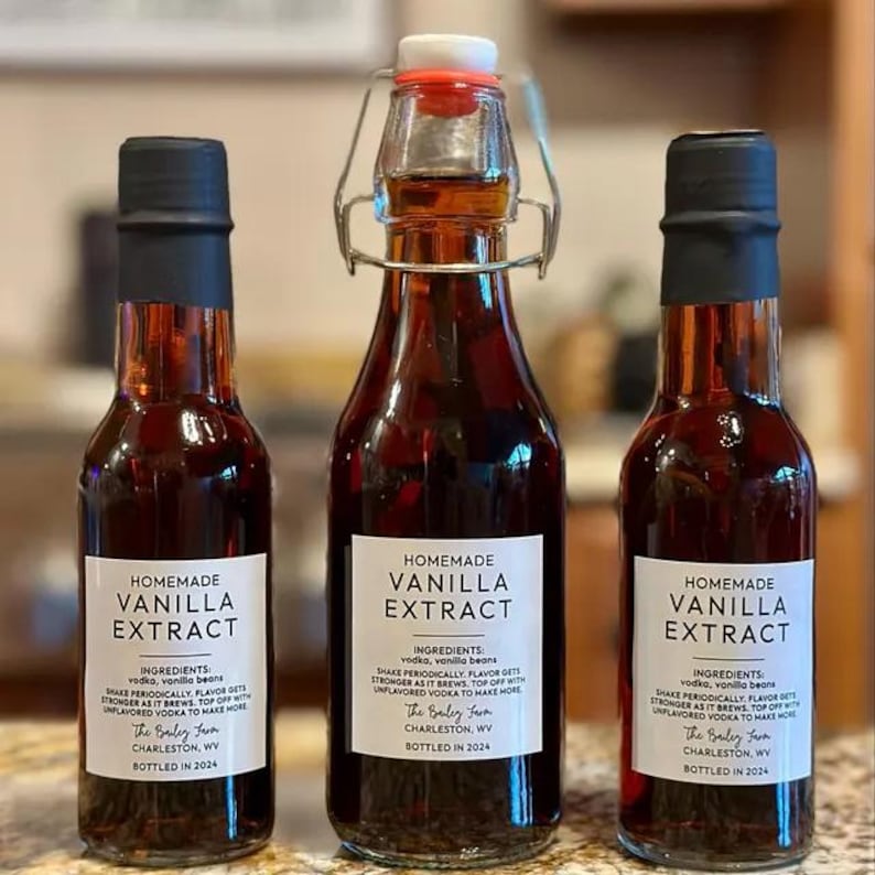 May include: Three glass bottles of homemade vanilla extract with labels that say "Homemade Vanilla Extract" and list the ingredients as vodka and vanilla beans. The labels also include the name "The Bailey Farm" and the location "Charleston, WV". The bottles are bottled in 2024.
