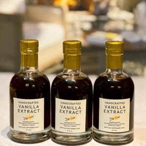 May include: Three glass bottles of handcrafted vanilla extract with gold lids. Each bottle has a label that reads "Handcrafted Vanilla Extract" with the ingredients listed as "Indonesian Vanilla Beans, Organic Vodka". The bottles are bottled in September 2024 and are 6.5 oz.