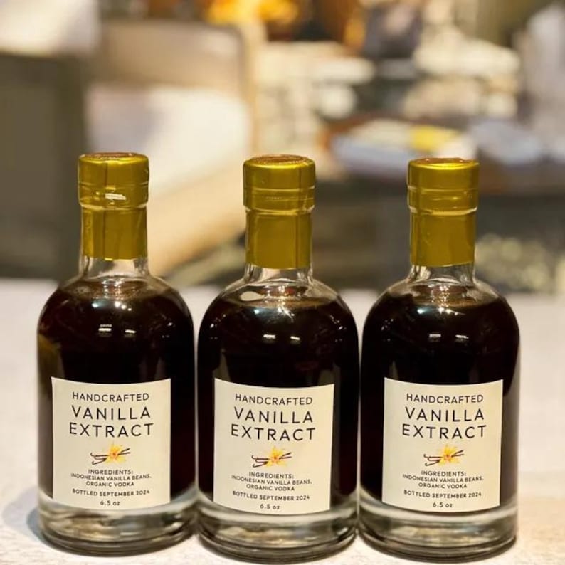 May include: Three glass bottles of handcrafted vanilla extract with gold lids. Each bottle has a label that reads "Handcrafted Vanilla Extract" with the ingredients listed as "Indonesian Vanilla Beans, Organic Vodka". The bottles are bottled in September 2024 and are 6.5 oz.