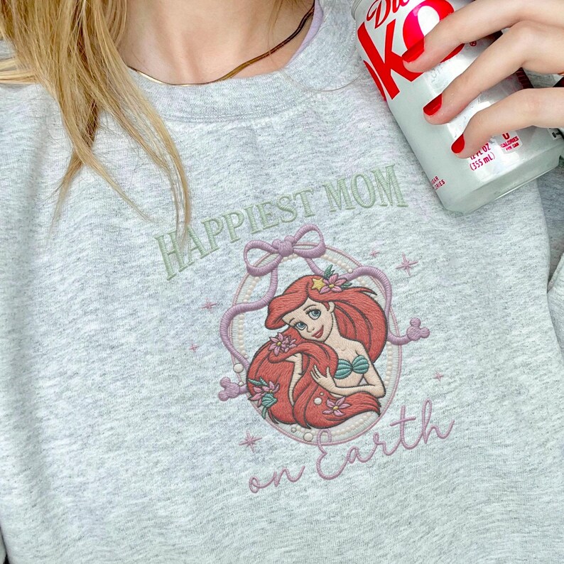 May include: A white ceramic mug with a black handle and the text "But First, Coffee" in a black, bold font. The mug is on a white surface.