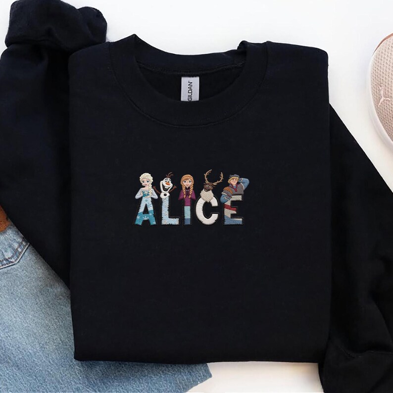 Może przedstawiać: Czarna bluza z okrągłym dekoltem z wyszytym imieniem "ALICE" w kolorowych literach, z postaciami z kresk&oacute;wek. Bluza wykonana jest z miękkiego materiału i ma klasyczny kr&oacute;j. Swobodny i wygodny element garderoby do noszenia na co dzień.